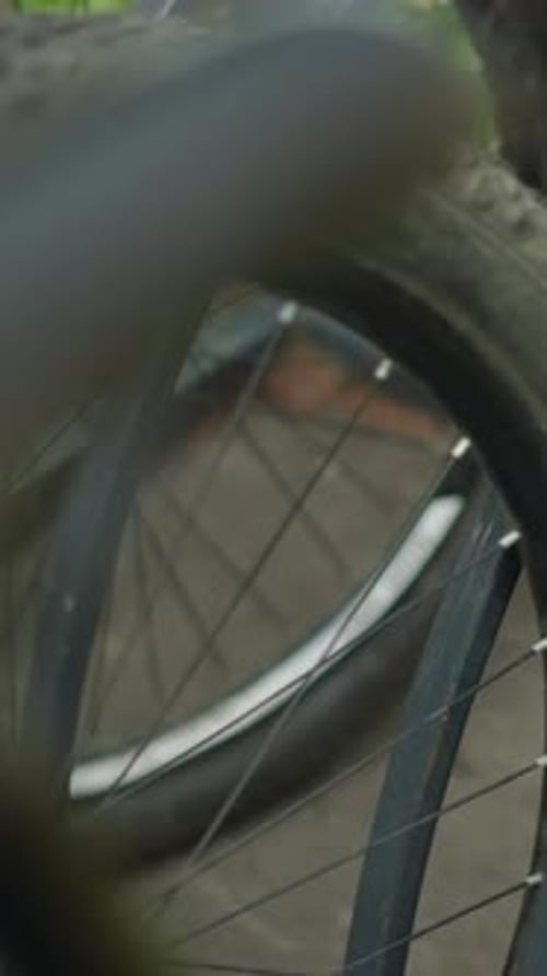 CloseUp of Bicycle Wheel Parked in Bike Rack with Blurred Background