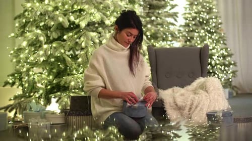 Woman Opens Gift Near Christmas Trees