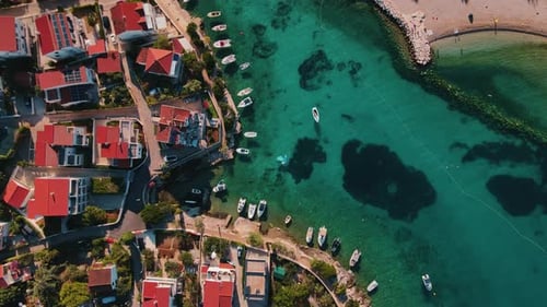 Drohnenaufnahme des Küstendorfs mit Booten, die im türkisfarbenen Wasser angedockt sind