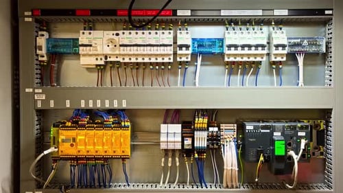 Industrial electrical control cabinet with PLC modules, breakers, relays, and neatly wired