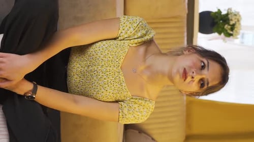 Young Woman Sits on Couch Indoors