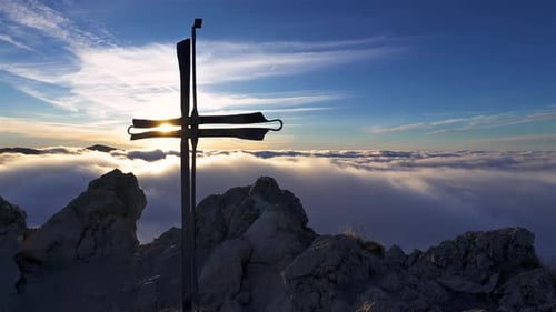 Mountain Peak with Summit Cross Glowing at Sunrise