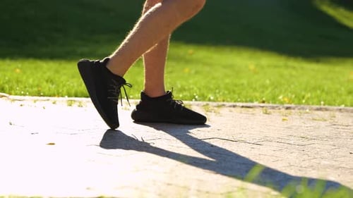 Caucasian Man Stretching Legs Before Outdoor Activities in Green Park on Sunny Summer Day Sportsman