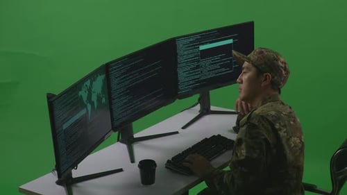 Side View Of Bored Asian Man Soldier Write Code With Multiple Computer Screens In Green Screen