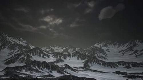 Aerial Flyover Over Vast Snowy Mountain Range Under Dark Sky