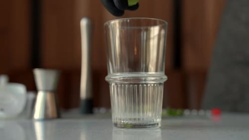 Gloved Hand Adding Lime into Cocktail Glass