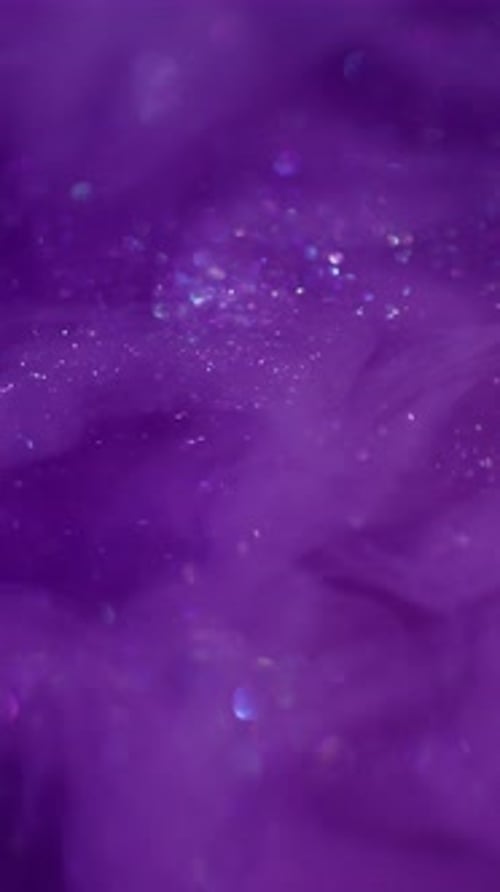 Sparkling Glitter Particles Flowing in Purple Liquid