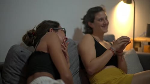 Slow motion of two latin girls sitting on a couch laughing and smiling having a lot of fun playing g