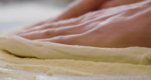 Nahaufnahme der Hände eines Pizzabäcks, der den Teig knetet, um eine Gourmet-Pizza zuzubereiten, und verteilt den Tom