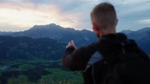 Man Points Toward The Rocky Mountains During Sunset