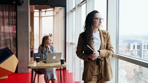 Tired business lady standing at the window. Busy office worker forgot about something.