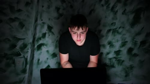 Concept de cyberintimidation : un adolescent lit des messages offensants sur un ordinateur portable et se couvre le visage