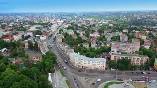 Main city street in the urban downtown. Cars running by the multilane road. Green park in the centre