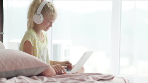 Blonde Schoolgirl Studying on Bed at Home Doing School Homework with Laptop Distance Learning Online