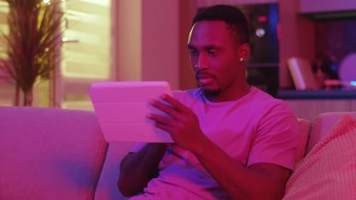 Man Relaxing on Couch Using Digital Tablet