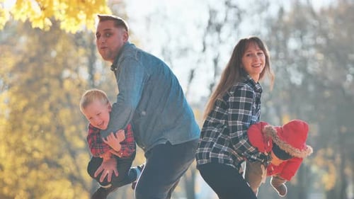 A Young Fun Family Playing with Their Children in the Park in the Fall