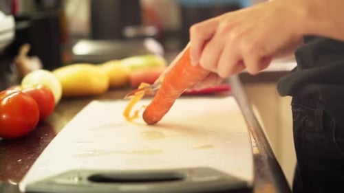 Woman Peeling Carrot in Kitchen