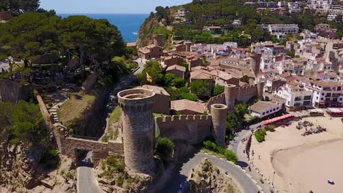 Flying to the left above a castle on the edge of the sea in Italy