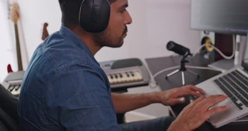 A musician is creating new music in his home studio.