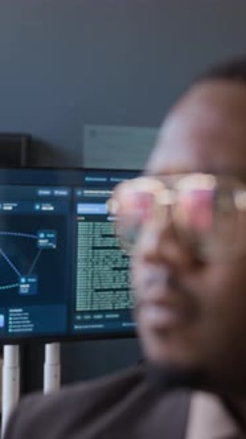 Portrait d'un ingénieur réseau noir travaillant au bureau avec des codes sur le moniteur