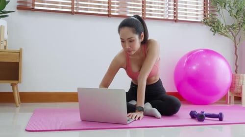 Woman Working Out at Home Using Laptop