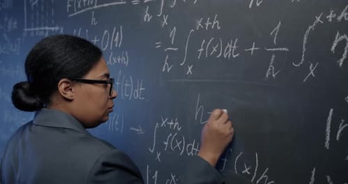 African American Woman Scientist Writing Formula on Chalkboard Thinking Concentrated on Calculation