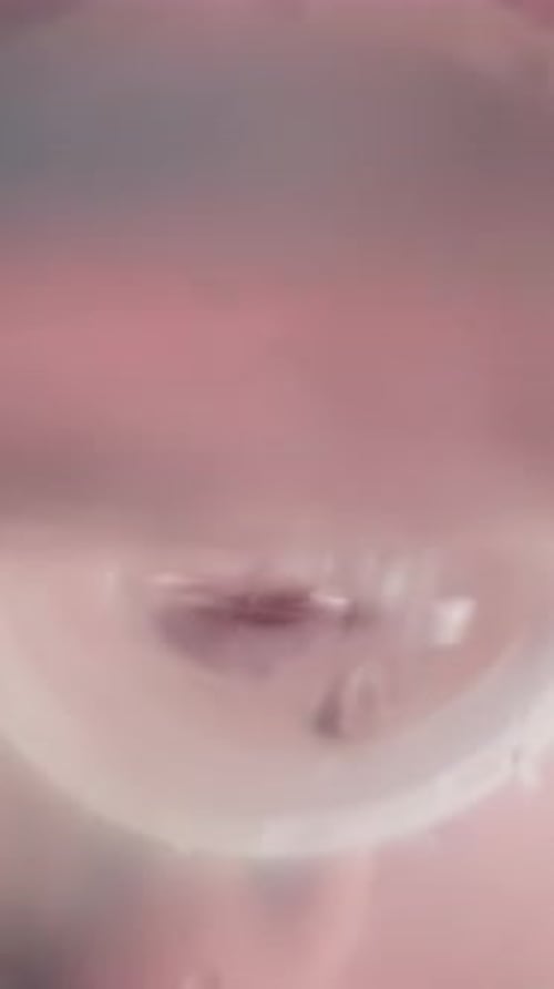 Una persona sedienta bebe una bebida rosa dulce del cuello de una botella