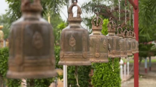 Bronze temple bells swinging in light rain, rack focus