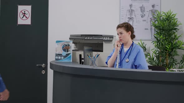 Medical Assistant Using Landline Phone Call at Hospital Reception Desk ...
