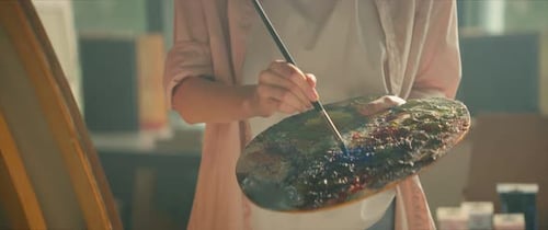 View on Woman Artist Painting with Oil Paint Picture on Canvas Hold Brush and Palette in Light Art