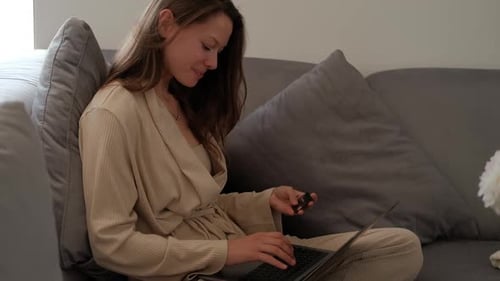 Woman on Sofa with Laptop and Credit Card