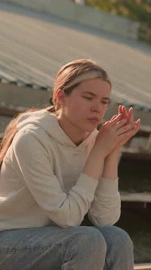 Woman Eats Fruit While Sitting on Metal Stairs
