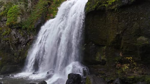 Waterfall in forest in the pacific northwest 4K drone footage ascending from base of waterfall.