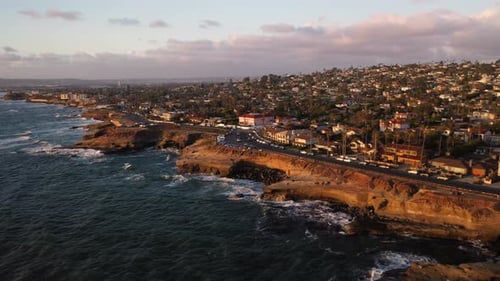 Sweeping aerial pan of waves and bluffs at Sunset Cliffs boulevard in San Diego