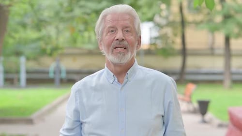 Smiling Mature Man Waving and Greeting in Park