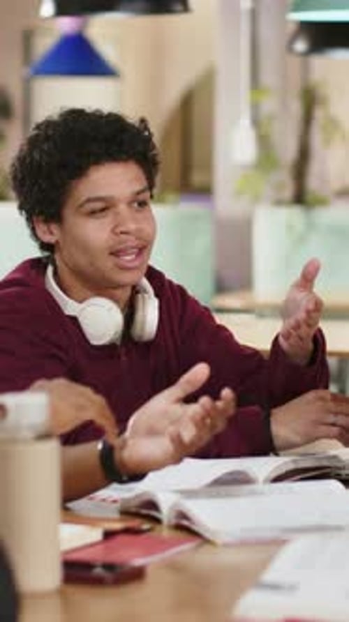 Vertical video: Answering peer prompt man in maroon sweatshirt gesturing at library with laptop