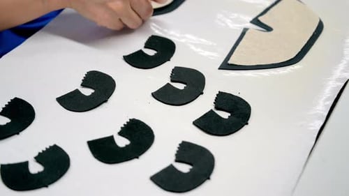 Worker Glues Textile to Leather Detail at Table in Workshop