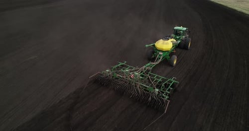 Top View of a Tractor Moving Through an Agricultural Field with Sowing Equipment