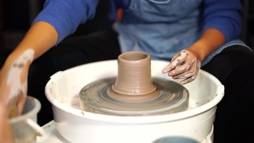 Closeup View of Potter's Hands with Working with Wet Clay on a Pottery Wheel Making a Clay