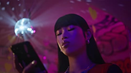 Stylish Woman Using Phone in Neon Disco Setting
