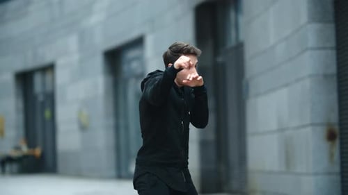 Young kickboxer training fist punch at outdoor workout in the city street