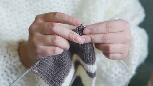 Woman Hand Knitting Gray and White Striped Garment