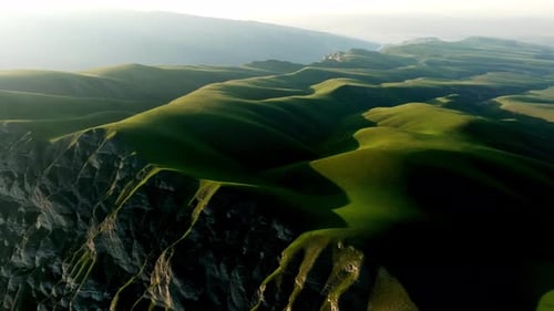 Amidst the Highlands a Sea of Vibrant Green Grass Under the Towering Mountains Iridescent Gradations