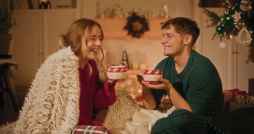 Smiling Couple Sharing Drinks in Christmas Setting