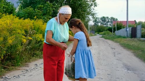 Grandmother Giving Apple to Young Girl in Countryside