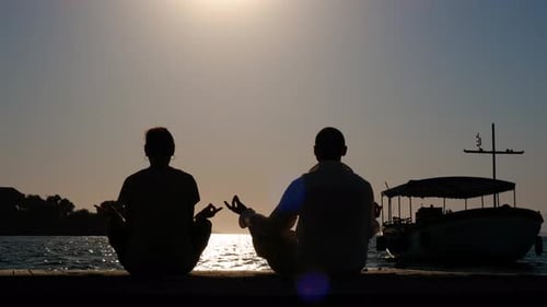 Couple Meditating on Dock at Sunset