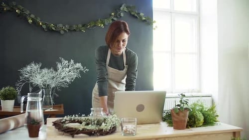 Young woman using laptop in flower shop startup florist business