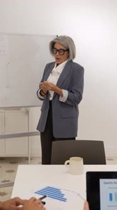 Businesswoman Presents Data on Whiteboard to Colleagues in Office