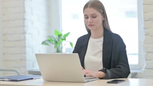 Young Woman Typing on Laptop Giving Thumbs Up