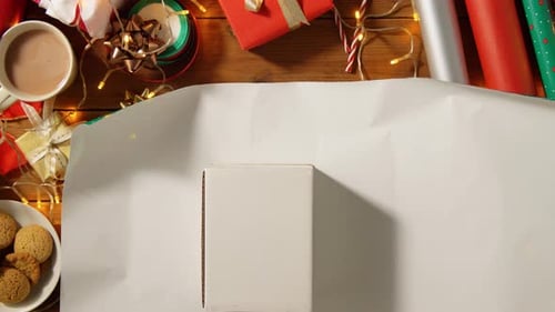 Overhead shot of hands wrapping Christmas gift on table